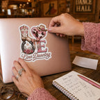 Woman applying a pink LOVE Line Dancing kiss-cut sticker to a rose-gold laptop at a country dance hall