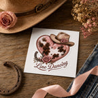 Pink cowhide heart Line Dancing sticker on its backing beside a cowboy hat, horseshoe and ribbon
