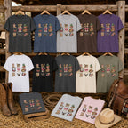 Western Icons graphic tees in available colours displayed on a rustic timber fence with cowboy boots and saddle