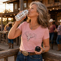 Woman drinking from a Western Icons stainless steel water bottle outside a rustic line dancing venue